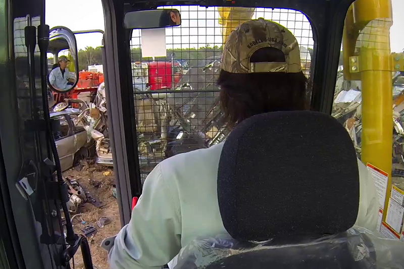 Over-the-shoulder view of an operator using the SK210D-11 Car Demolition Excavator