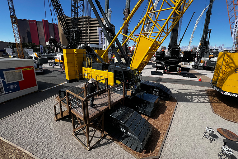 Aerial view of an attendee on a stage looking at the cab of a large crane