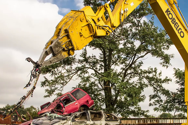 Wide shot of the SK210D-11 Car Demolition Excavator's boom raised up in the air. 