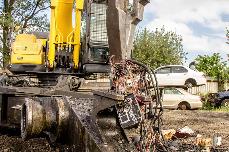 Medium shot of electrical wiring being removed from scrap car with KOBELCO SK210D-11 Car Demolition Excavator